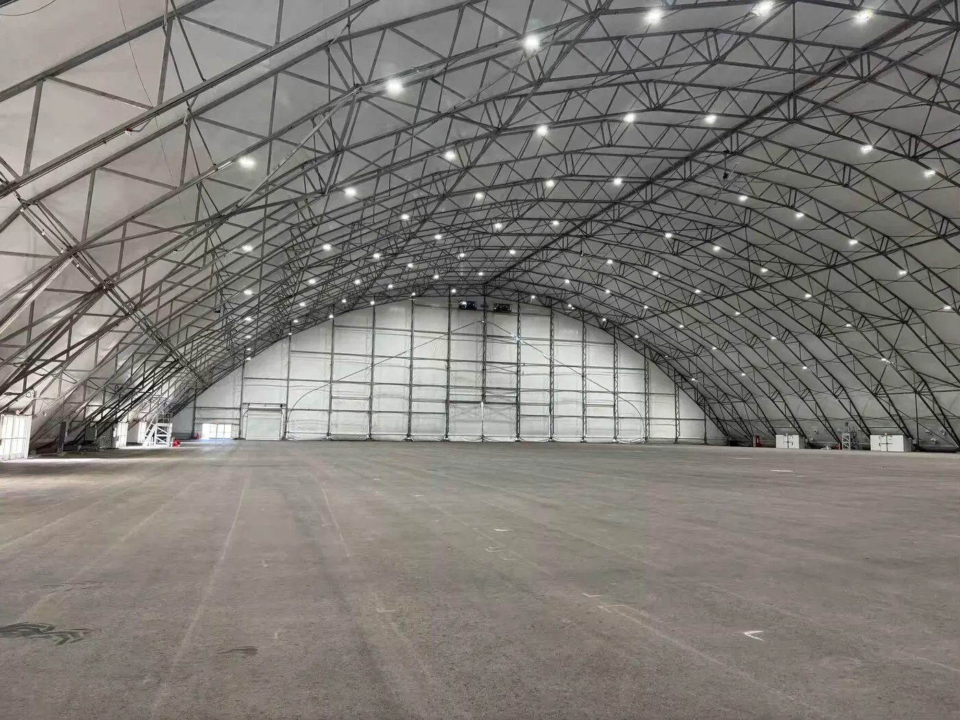 Finished interior slab and pad inside a large clear-span fabric structure