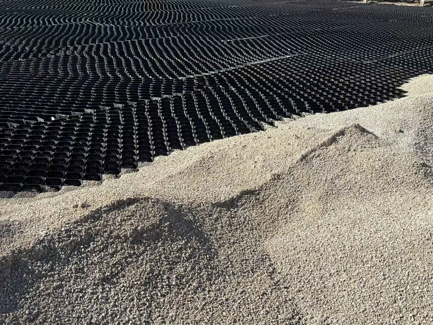 Expanded geocell panels laid across a prepared subgrade before aggregate infill