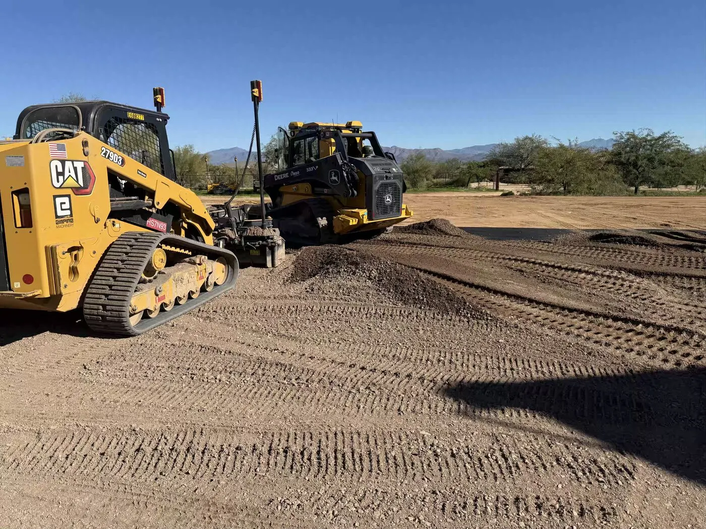 Skid steer with laser grading box shaping a pad in the Arizona desert
